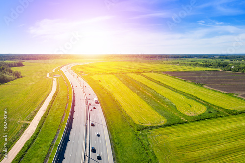 Asphalt Speedway with cars through green field near forest photo