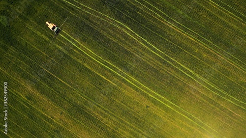 Obraz na plátně Birds-eye view of a tractor working in a green field