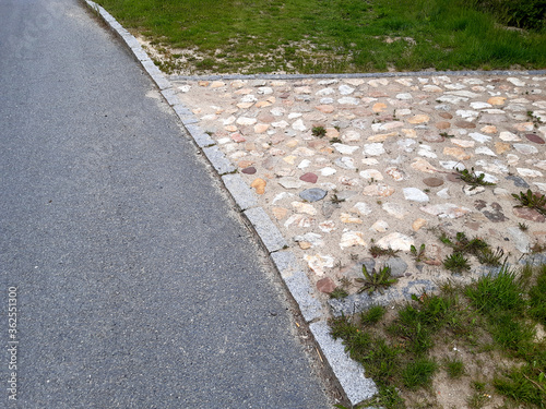 rural stone paving urban square made of quartz cobbles size about 15cm joints filled with gravel brown beige white yellow color of pebbles in connection with the cobblestone gray sidewalk and curbs photo