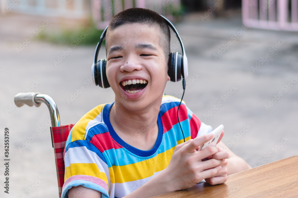 Special need child on wheelchair wear headphones use smartphone