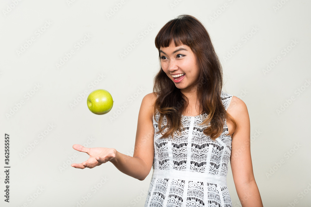 Portrait of happy young beautiful Asian woman throwing apple Portrait of happy young beautiful Asian woman throwing apple