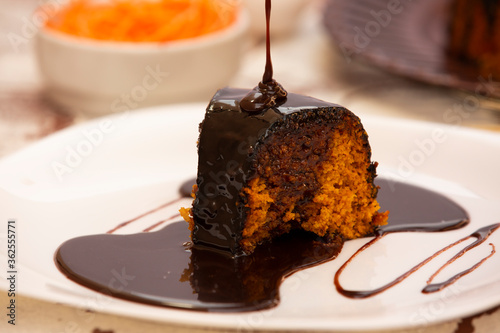 Carrot cake with chocolate and slice on the table.