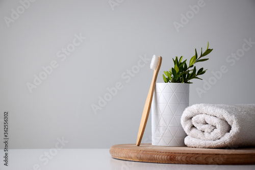 Eco wooden toothbrush, white holder and fresh white towel on wooden round board. Dental treatment or beauty care concept. Copy space. photo