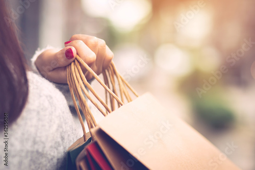 Closeup of woman hand holding shopping bag colorful paper on the street happy summer with copy space.