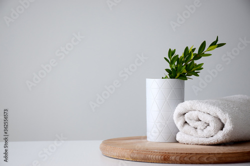 White container and green herb, white rolled towel on wooden board. Spa or beauty care concept. Copy space.