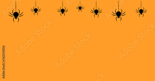 Halloween orange background decoration with spider hanging on a thread © Hodomych