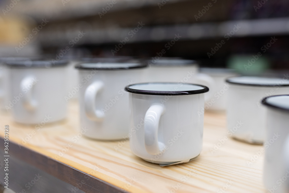 white metal enameled mugs standing on a store counter white metal enameled mugs standing on a store counter