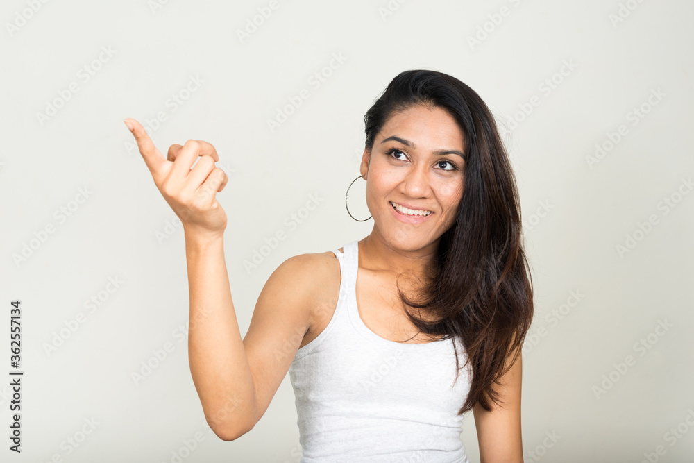 Portrait of happy Asian woman thinking and pointing finger Portrait of happy Asian woman thinking and pointing finger