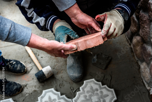Worker holds a concrete pavement tile. The concept of work on laying figured decorative paving slabs.