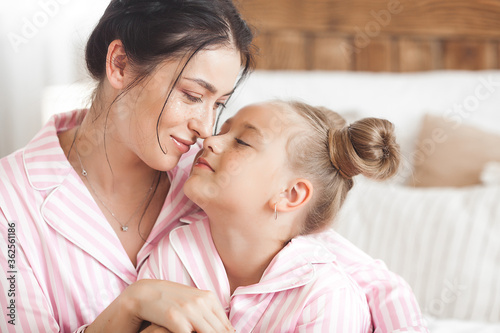 Attracive young mother and her little daughter in the bedroom.