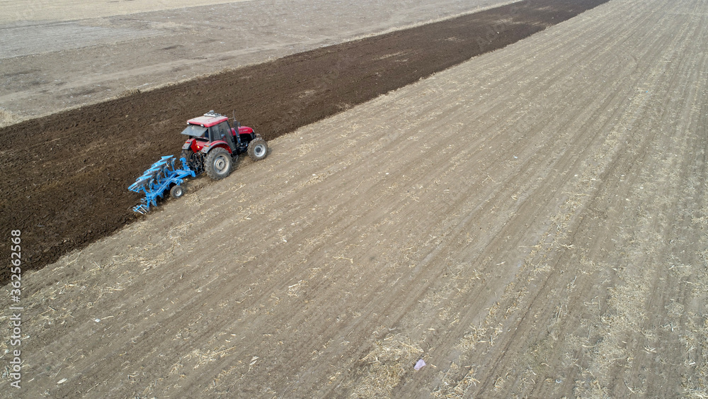 Farmers flatten their land with turning ploughs for spring ploughing