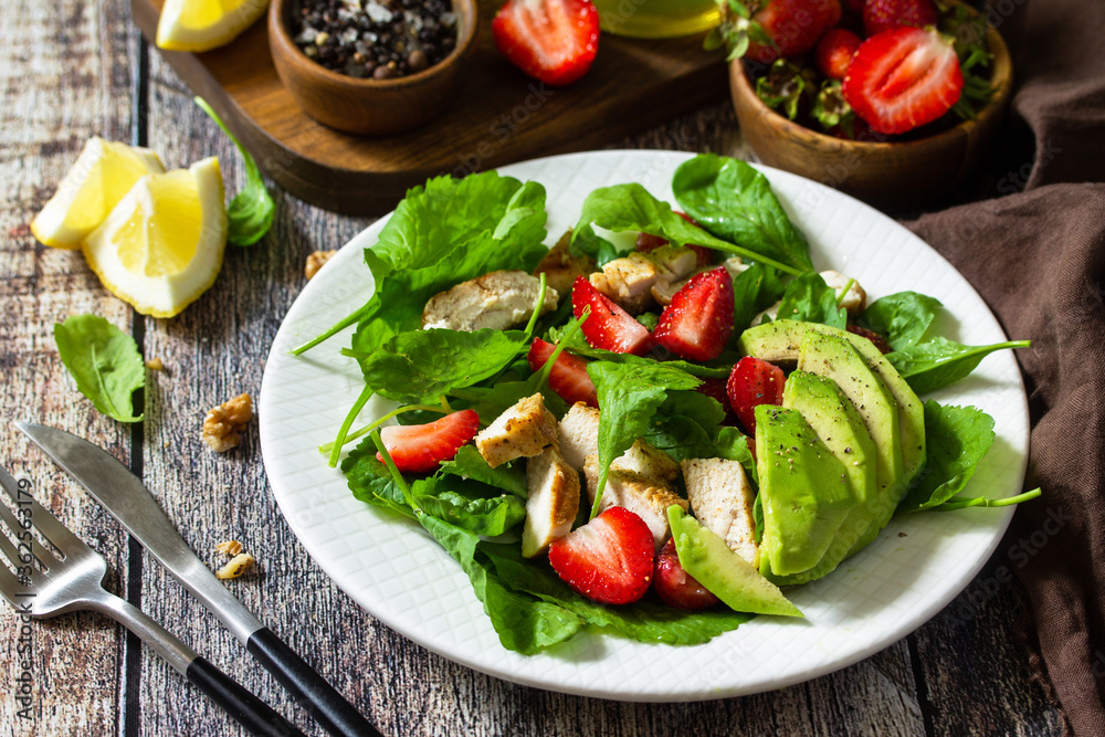 Lunch for keto. Summer salad with strawberries, grilled chicken and avocado on a rustic table.