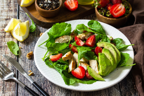 Lunch for keto. Summer salad with strawberries, grilled chicken and avocado on a rustic table.