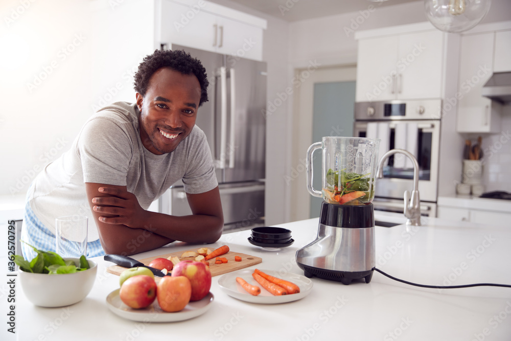 Portrait Of Man Wearing Pyjamas Standing In Kitchen Chopping Fruit And Vegetables For Fresh Smoothie Portrait Of Man Wearing Pyjamas Standing In Kitchen Chopping Fruit And Vegetables For Fresh Smoothie