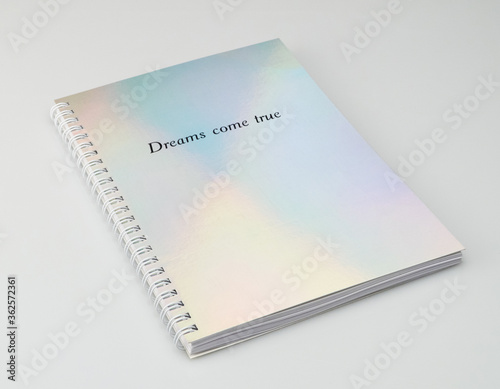 a notebook with iridiscent cover and motivational text, white background