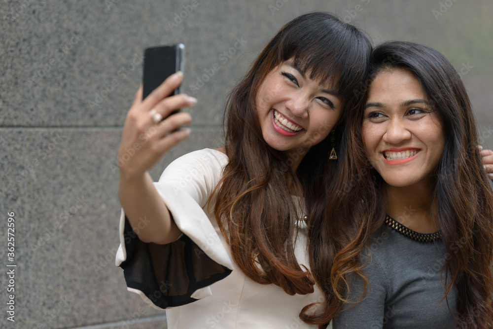 Two happy young Asian businesswomen together in the city Two happy young Asian businesswomen together in the city