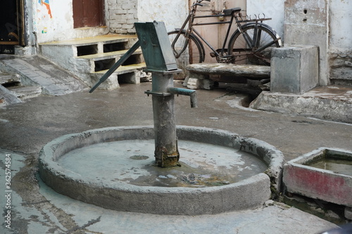 Old hand operated water pump and water containers in rural India. Hand water pump in old city. Very Old Vintage Hand Manual Pump.