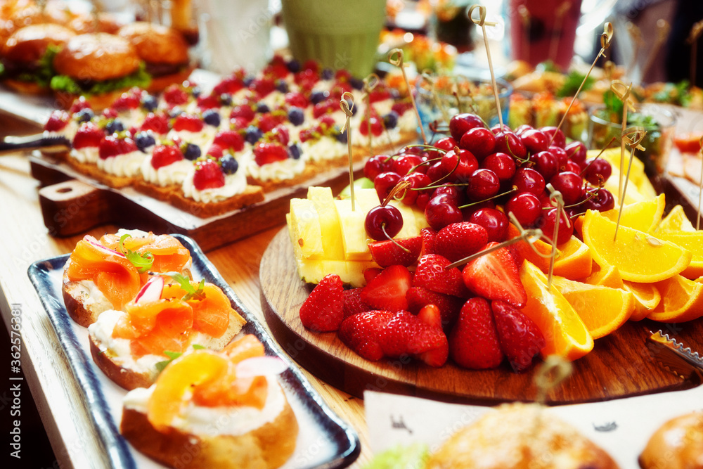 Fruits, fish snacks and dessert on catering table, toned Fruits, fish snacks and dessert on catering table, toned