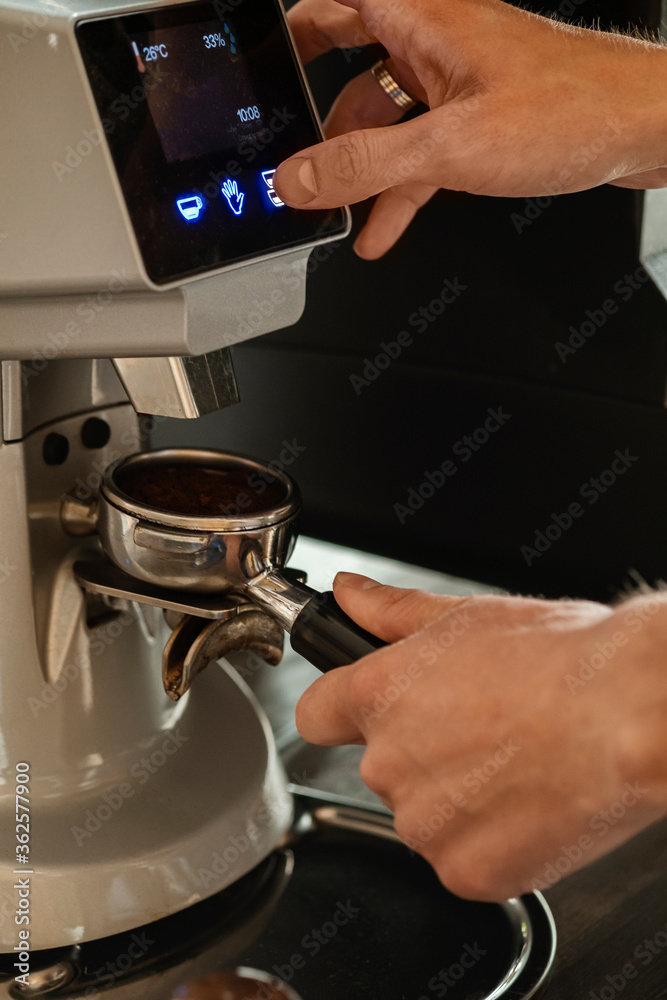 Closeup of barista grinding coffee. Professional barista working makeing coffee with coffee machine. Hot pouring drink concept. Toned picture