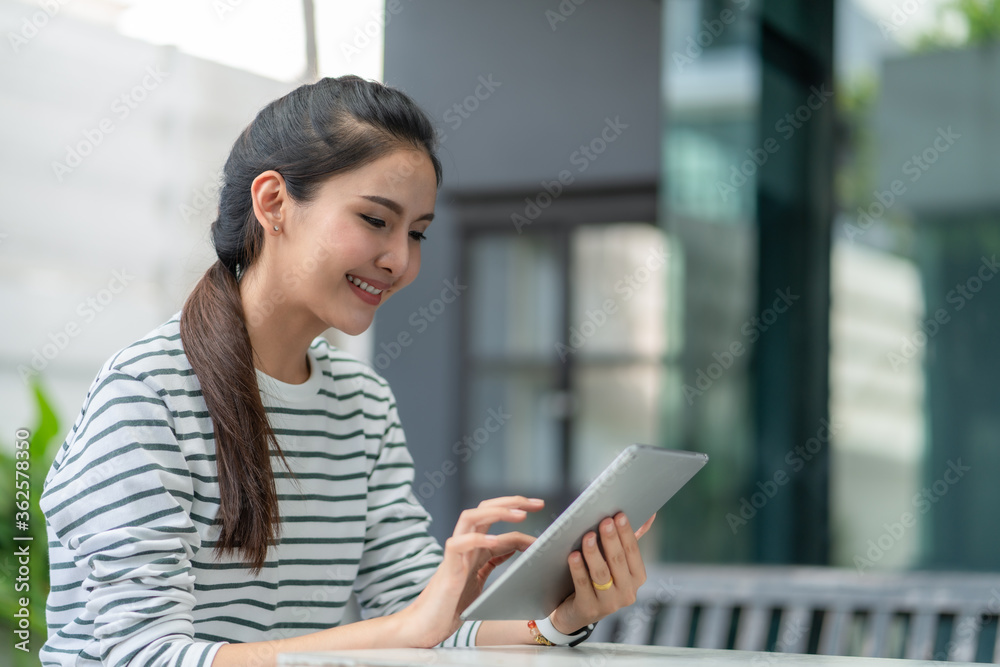 Asian young woman smiling while using tablet at home Asian young woman smiling while using tablet at home