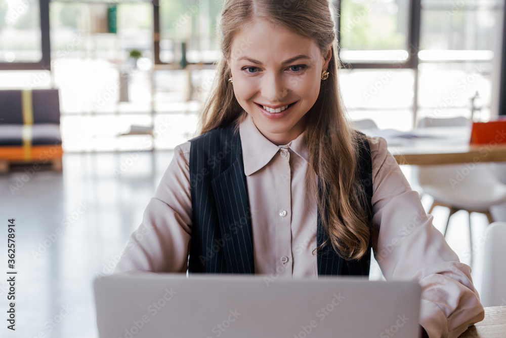 selective focus of happy businesswoman using laptop in office selective focus of happy businesswoman using laptop in office