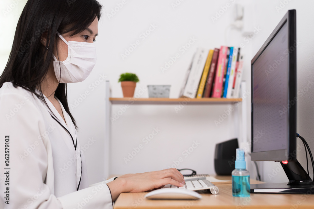 A beautiful Asian businesswoman wearing a mask and cleaner gel to protect COVID-19 before start working from home with safety and happiness. A beautiful Asian businesswoman wearing a mask and cleaner gel to protect COVID-19 before start working from home with safety and happiness.