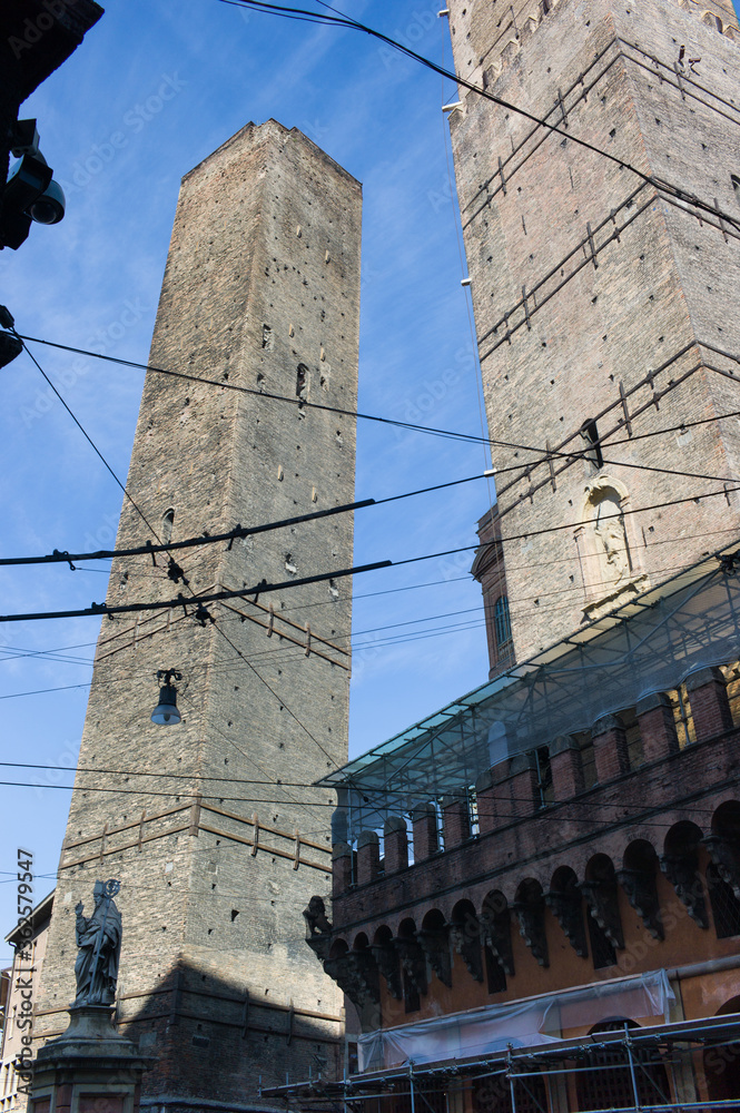 2013: The two famous towers of Bologna, Garisenda and Asinelli surrounded by electricity cables, at the intersection of the roads to the five gates of the old ring wall