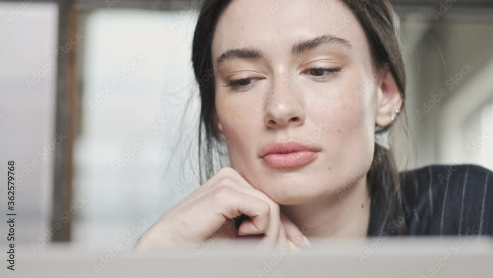 Close-up view of a gorgeous thinking young businesswoman is using her laptop computer while working in the office Close-up view of a gorgeous thinking young businesswoman is using her laptop computer while working in the office