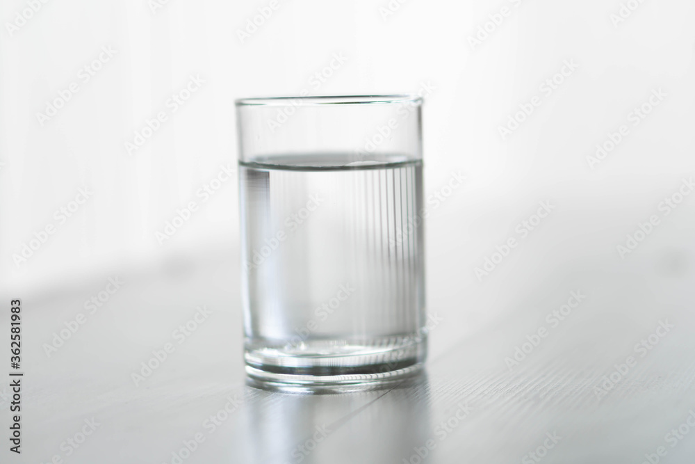 Glass of water on wood table with light in the morning, healthy care concept, selective focus Glass of water on wood table with light in the morning, healthy care concept, selective focus