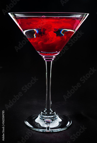 Martini glass with red turbulence in liquid on black background