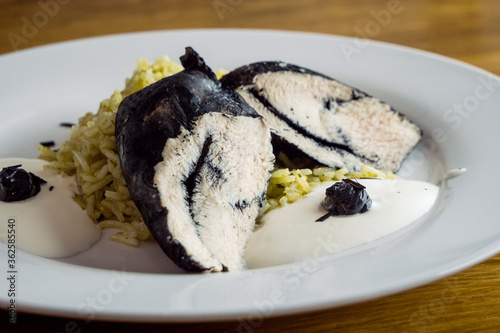 Dish of boiled white rice and chicken fillet colored black with cuttlefish ink.