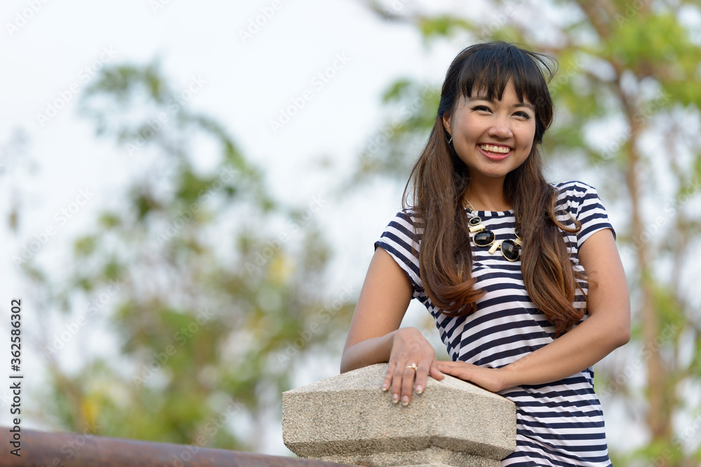 Happy young beautiful Asian woman at the park Happy young beautiful Asian woman at the park