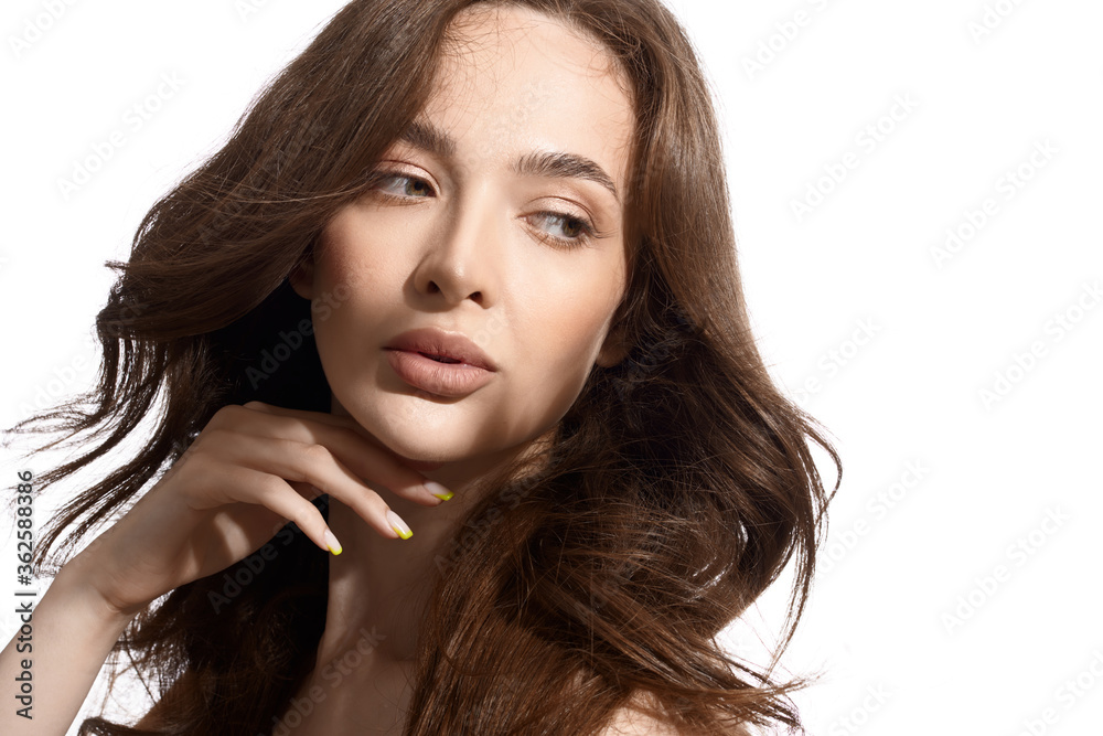 Beautiful young brunette with natural make-up and silk long hair on a white background. Shadow on the face. Woman looking at camera. Isolated over white background. Beautiful young brunette with natural make-up and silk long hair on a white background. Shadow on the face. Woman looking at camera. Isolated over white background.