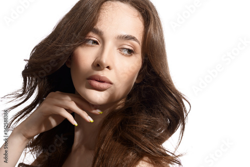 Beautiful young brunette with natural make-up and silk long hair on a white background. Shadow on the face. Woman looking at camera. Isolated over white background.
