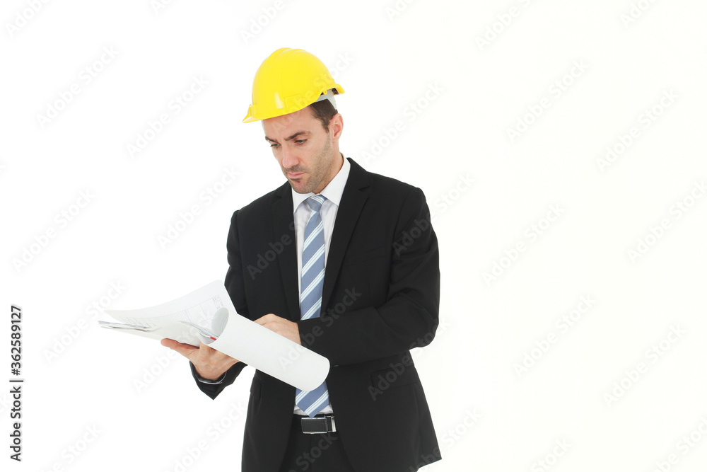 Handsome and smart engineer in black suit Wearing a yellow safety engineer hat with hand holding Construction drawing papers and serious in work isolated on yellow background. Copy Space Handsome and smart engineer in black suit Wearing a yellow safety engineer hat with hand holding Construction drawing papers and serious in work isolated on yellow background. Copy Space