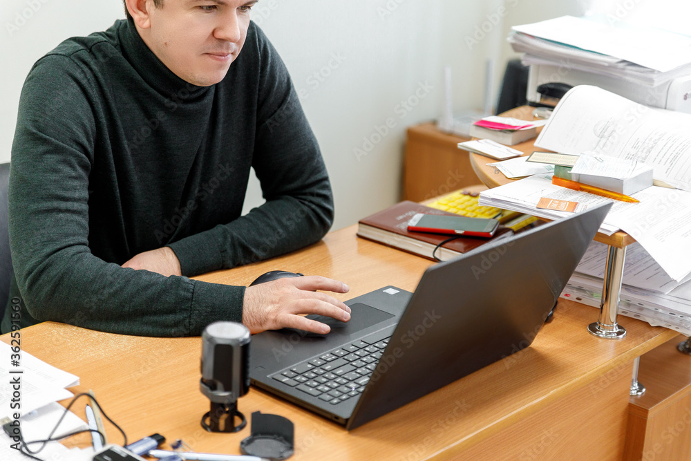 Businessman at work. Close-up top view of man working on laptop while sitting at the wooden desk Businessman at work. Close-up top view of man working on laptop while sitting at the wooden desk