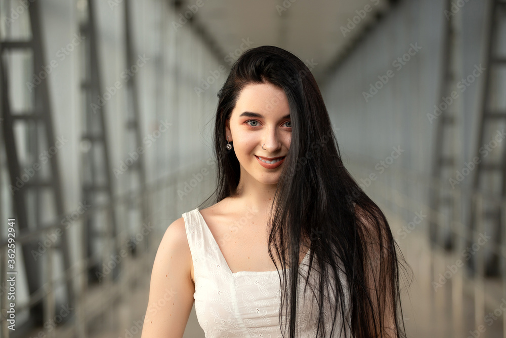 Portrait of a beautiful brunette in a light dress on the street in a pedestrian crossing on a summer day