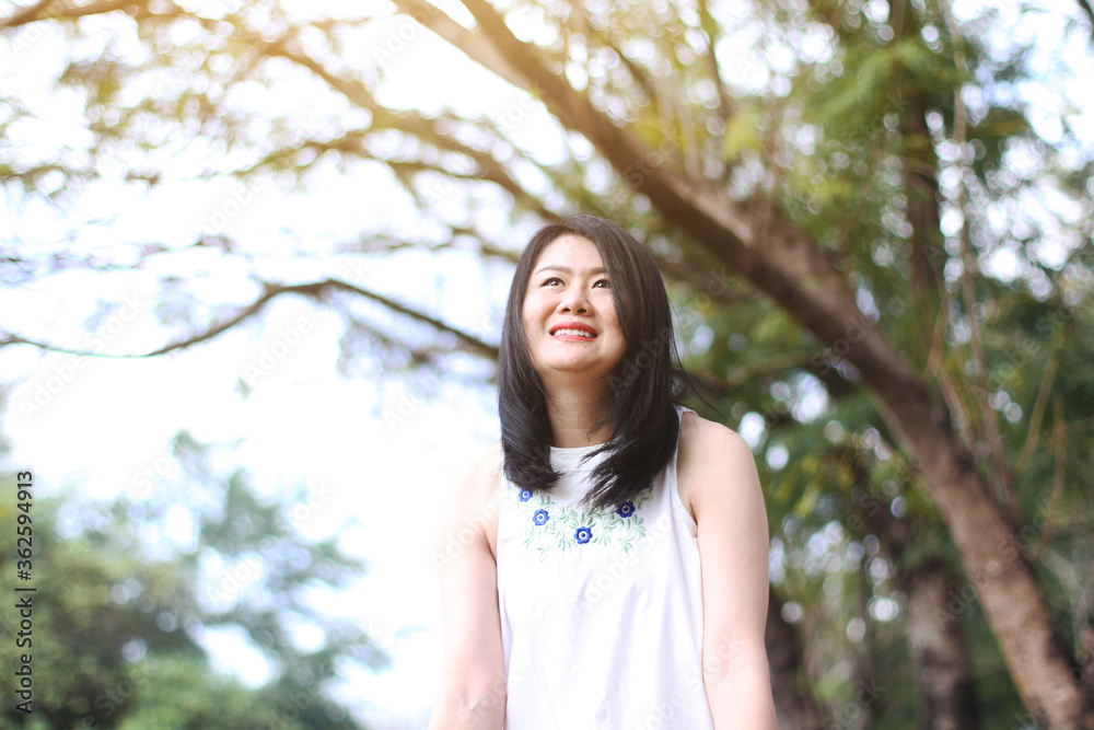 Beautiful asian woman in white dress relax and smiling in nature park. Thai girl or Chinese Girl enjoy on holiday Beautiful asian woman in white dress relax and smiling in nature park. Thai girl or Chinese Girl enjoy on holiday