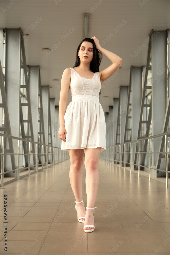 Portrait of a beautiful brunette in a light dress on the street in a pedestrian crossing on a summer day Portrait of a beautiful brunette in a light dress on the street in a pedestrian crossing on a summer day