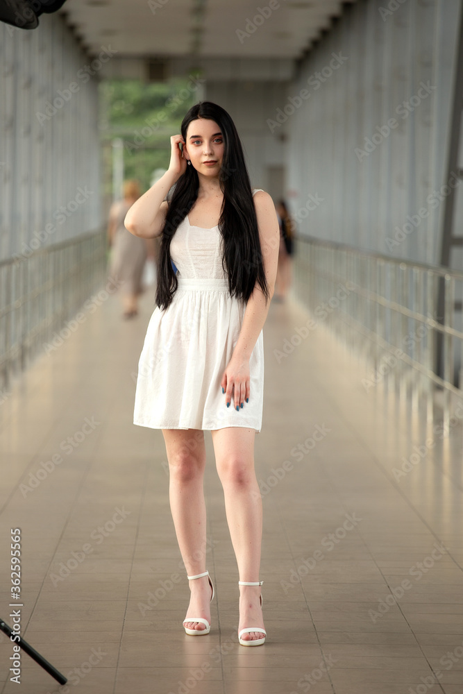 Portrait of a beautiful brunette in a light dress on the street in a pedestrian crossing on a summer day Portrait of a beautiful brunette in a light dress on the street in a pedestrian crossing on a summer day