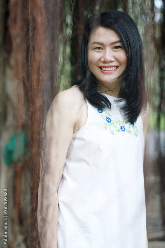 Beautiful asian woman in white dress smiling and laugh in natural park. Thai girl or Chinese Girl enjoy on holiday with sunlight in garden Beautiful asian woman in white dress smiling and laugh in natural park. Thai girl or Chinese Girl enjoy on holiday with sunlight in garden