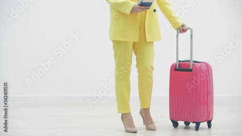 Cropped slowmotion video of female carrying a suitcase and passport over white background with copyspace. photo