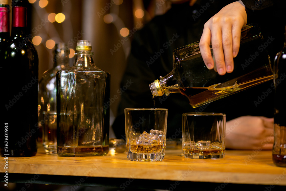 Barman pouring whiskey glass beautiful night