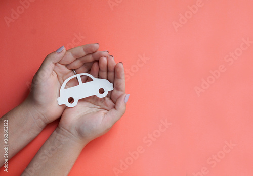 hands holding paper car cutout, on the color background, family protection concept