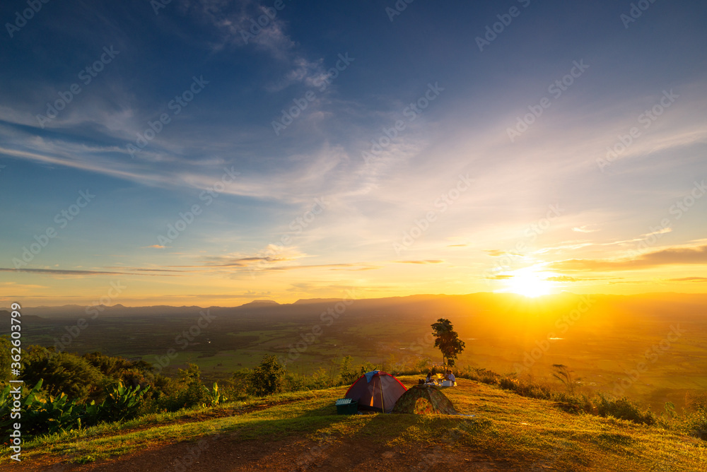 Tourists are partying next to the tent in the camping ground during the sunset (tourists face are blurred). Tourists are partying next to the tent in the camping ground during the sunset (tourists face are blurred).