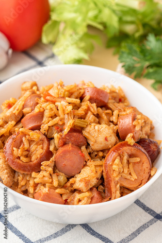 Creole jambalaya (also called "red jambalaya"). Jambalaya with chicken, sausages and vegetables in a white bowl on the table close-up.