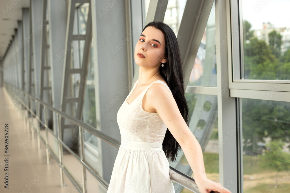 Portrait of a beautiful brunette in a light dress on the street in a pedestrian crossing on a summer day Portrait of a beautiful brunette in a light dress on the street in a pedestrian crossing on a summer day