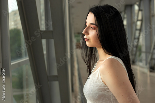 Portrait of a beautiful brunette in a light dress on the street in a pedestrian crossing on a summer day