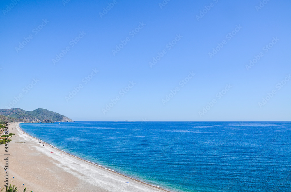 Summer mediterranean coastal landscape. View of Cirali Beach from ancient Olympos ruins, with mountains and pine trees in background Antalya Turkey.