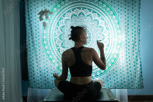 Young queer non binary person smoking and doing yoga 